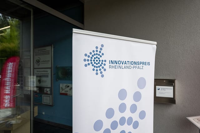 Innovaatiopalkinto Rheinland-Pfalzin banderolli sisäänkäynnin edessä