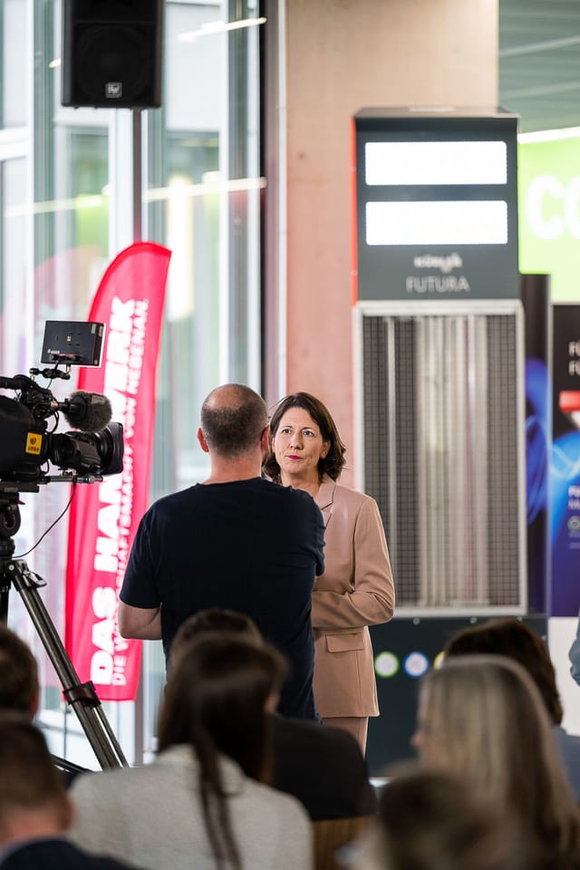 Nainen antaa haastattelun televisioryhmälle modernissa rakennuksessa
