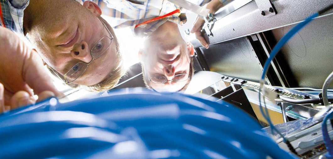 Nahaufnahme von zwei Mitarbeitern, die Kabel eines Heizungssystems überprüfen