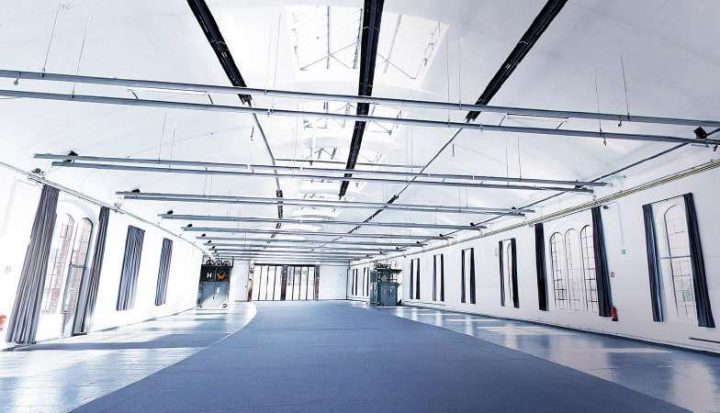 Beleuchtete Ausstellungshalle mit langen Fenstern mit abgerundeten Enden und blauen Vorhängen