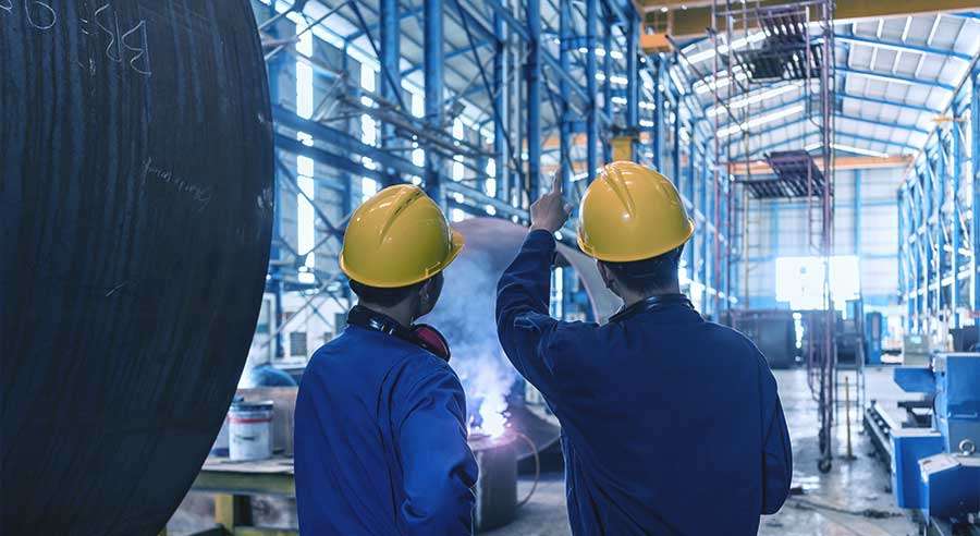 Arbeiter in Schutzhelmen inspizieren Fabrikausrüstung.