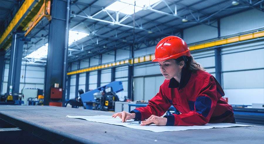 Ingeniør sjekker byggeplan i en fabrikkbygning.