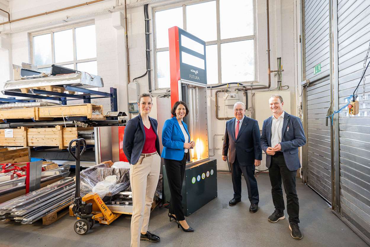 Daniela Schmitt in the KÜBLER production hall with three other people in front of the FUTURA model