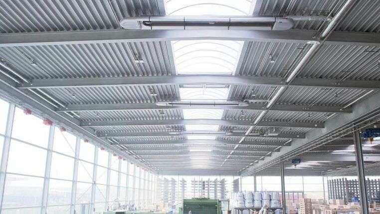 Industriehalle mit Metallkonstruktion und FensternAGroße Logistikhalle mit weißen OPTIMA plus Hallenheizungssystem von KÜBLER