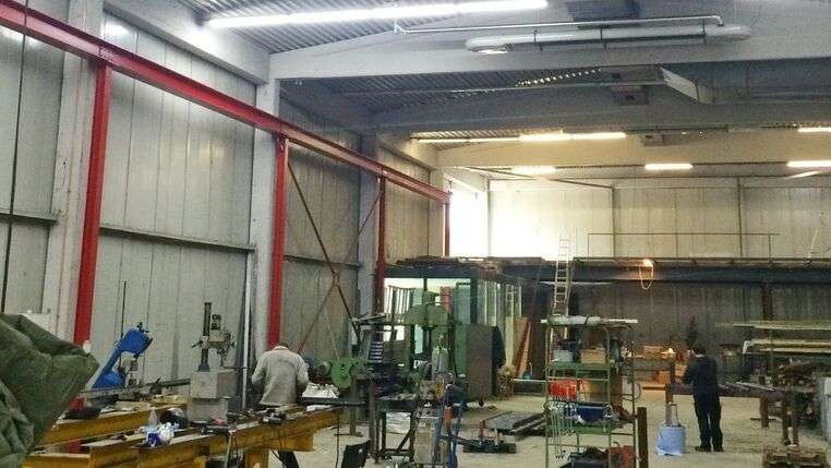 Innenansicht einer belebten Werkshalle.aSchlosserei ausgestattet mit weißen OPTIMA plus Dunkelstrahlern von KÜBLER