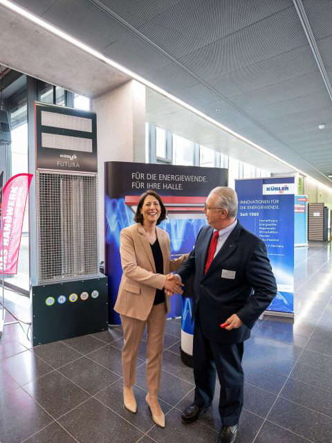 Two people shake hands at a trade fair.