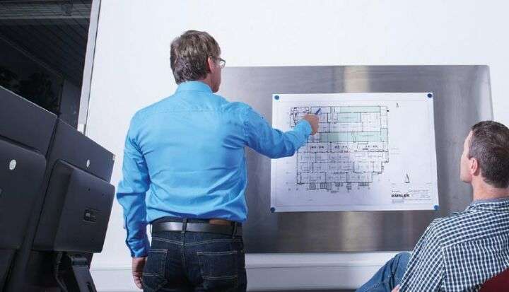 Männer betrachten Bauplan an Wand