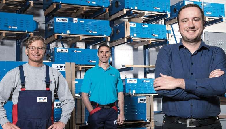 Tre ansatte på lageret med blå esker.