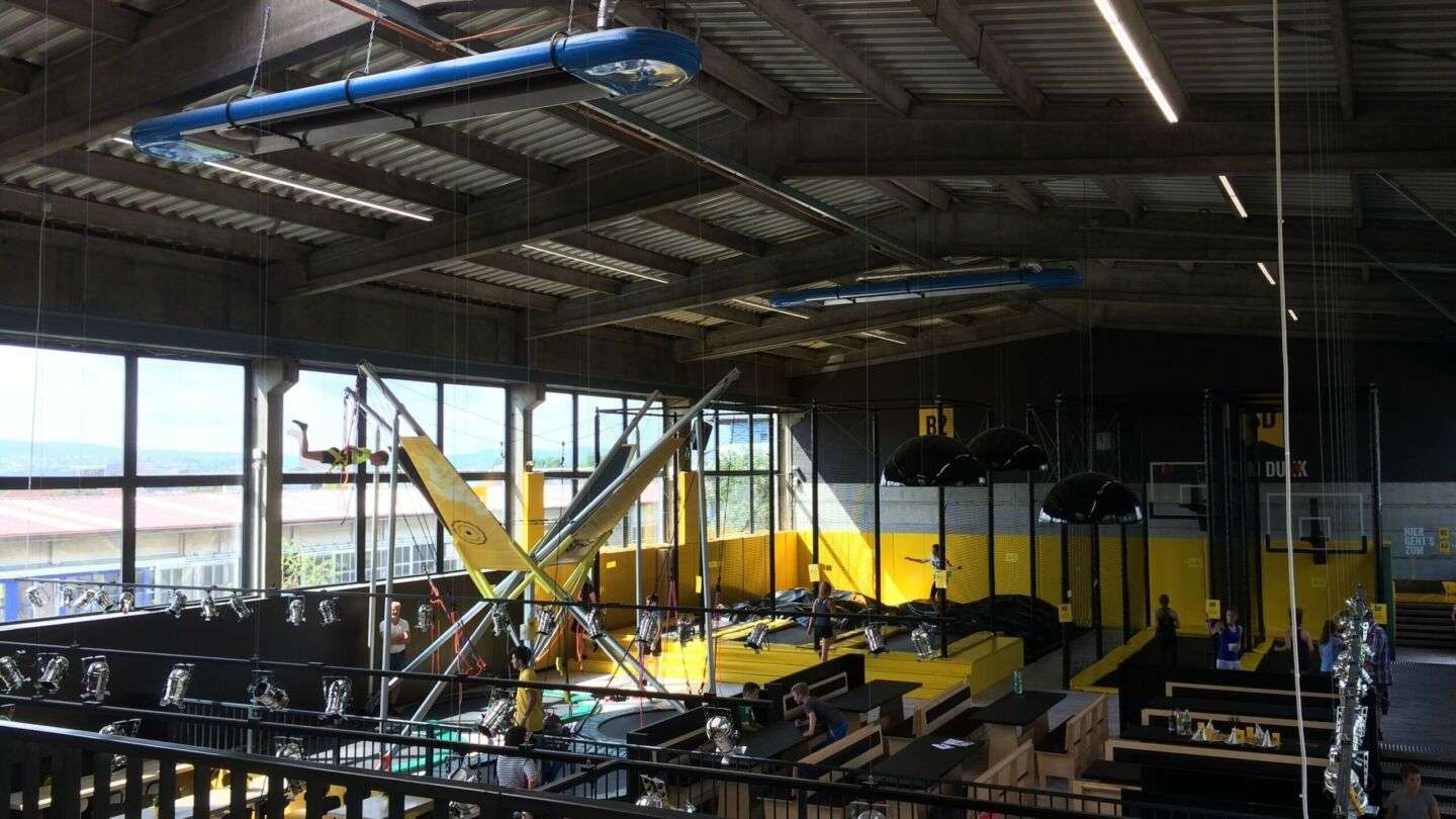 Innenansicht einer Trampolinhalle mit Besuchern.