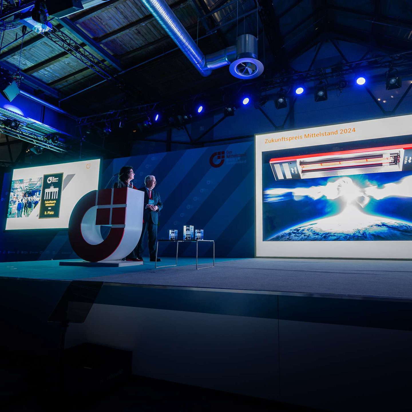 Vállalati rendezvény színpadi bemutatóval és nagy képernyővel.