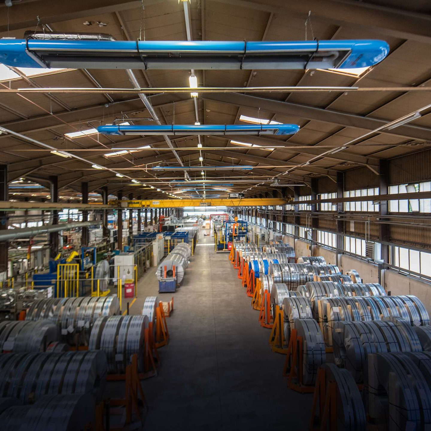 Teollisuushalli, jossa kaapelirummut ovat rivissä.