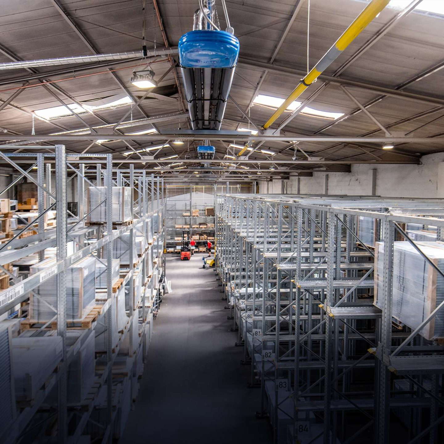 Teollisuusvarasto, jossa on korkeita hyllyjä ja trukkeja.
