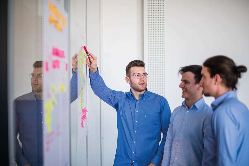 Men at a team meeting with sticky notes.