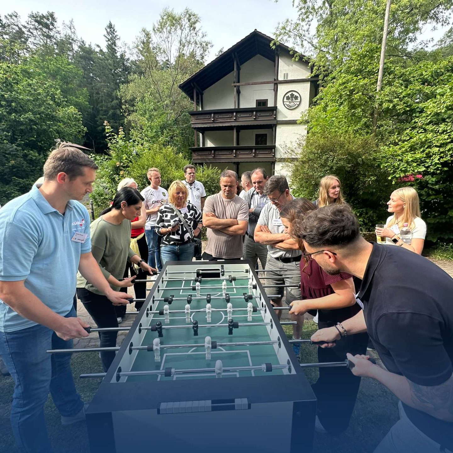Gruppe spielt Tischfußball im Freien.