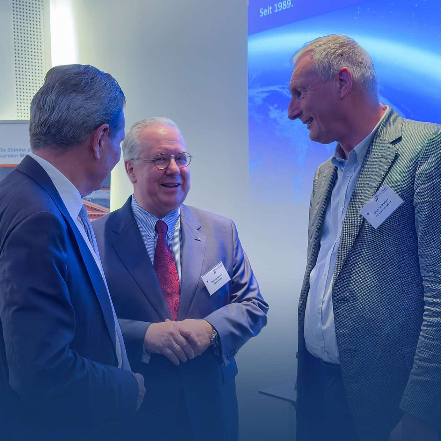 Három üzletember mosolyog és beszélget.