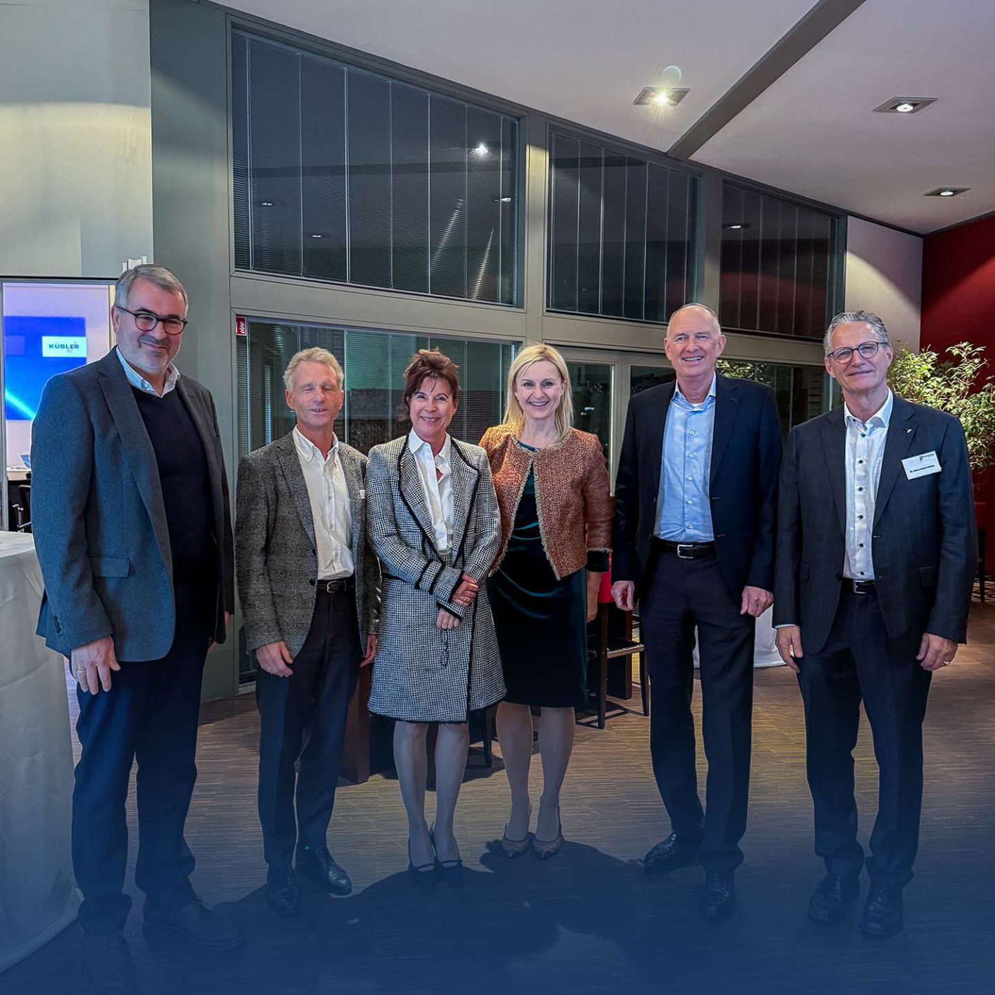 Hat üzletember mosolyog egy irodai környezetben