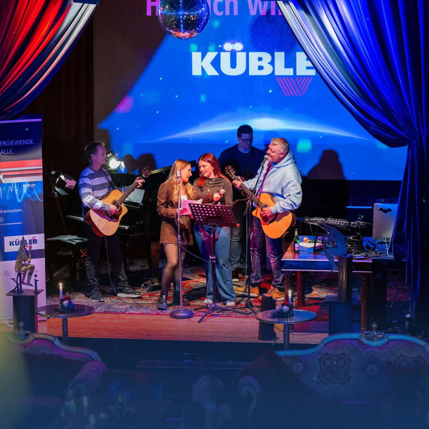 Bändi soittaa livenä lavalla diskopallon kanssa.