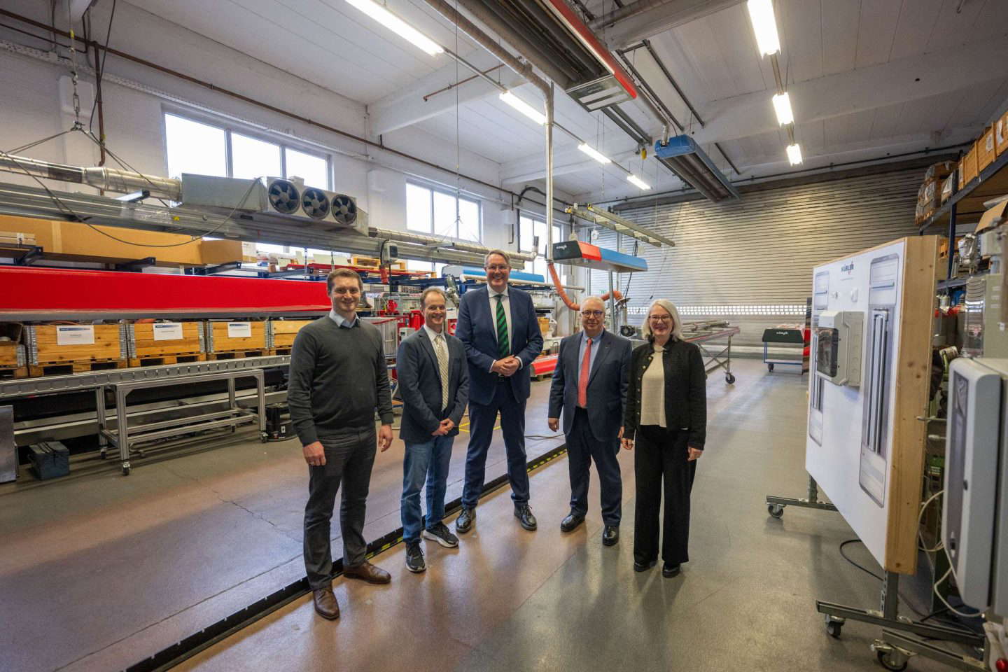 Fünf Personen in einer Industriehalle lächeln