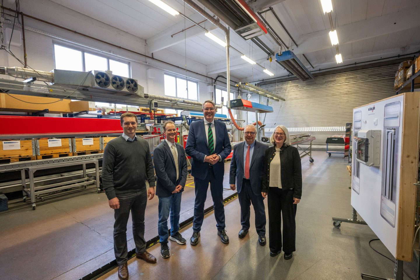 Fünf Personen in einer industriellen Werkhalle