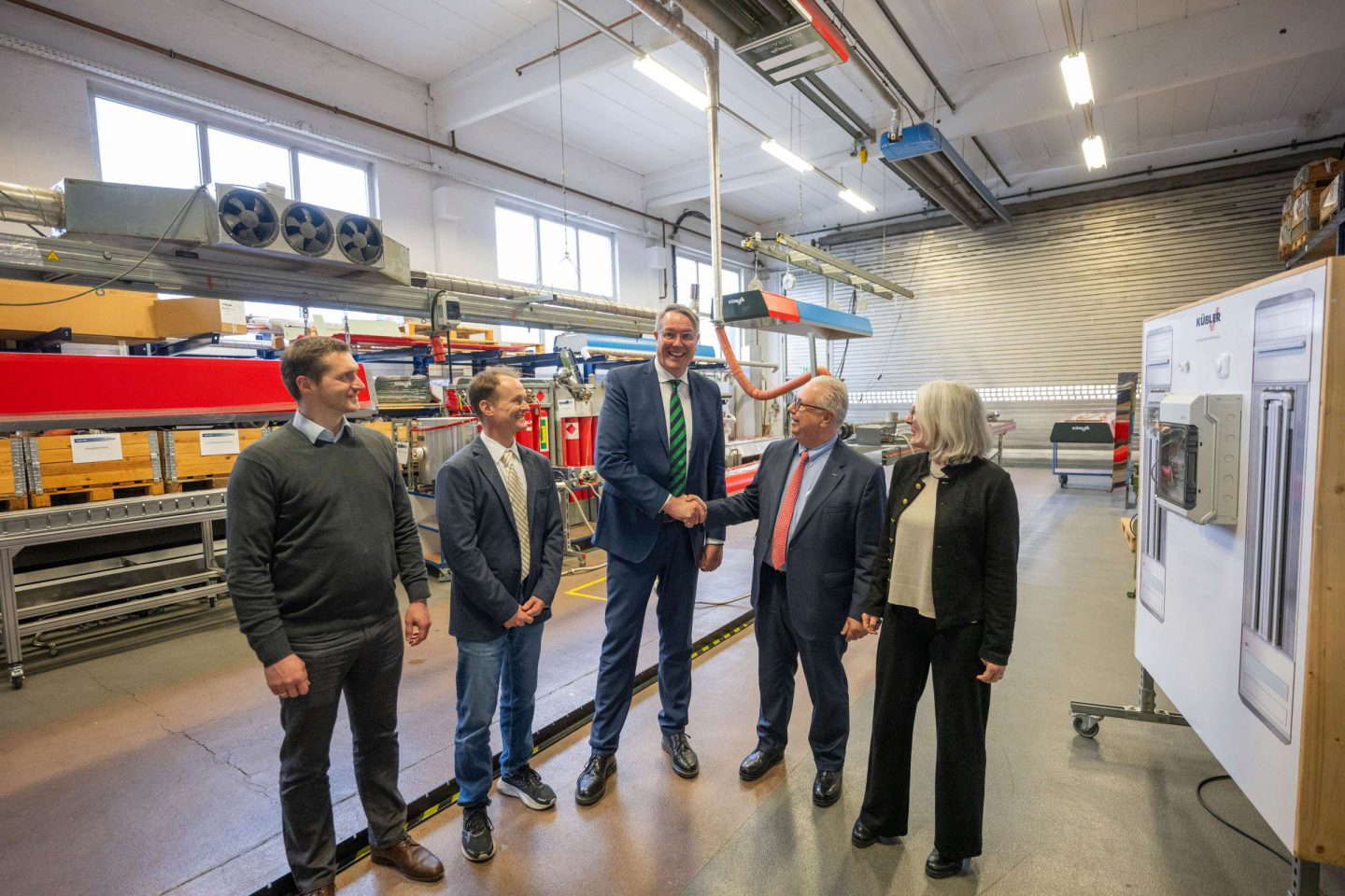 Männer und Frau beim Handschlag in Fabrik