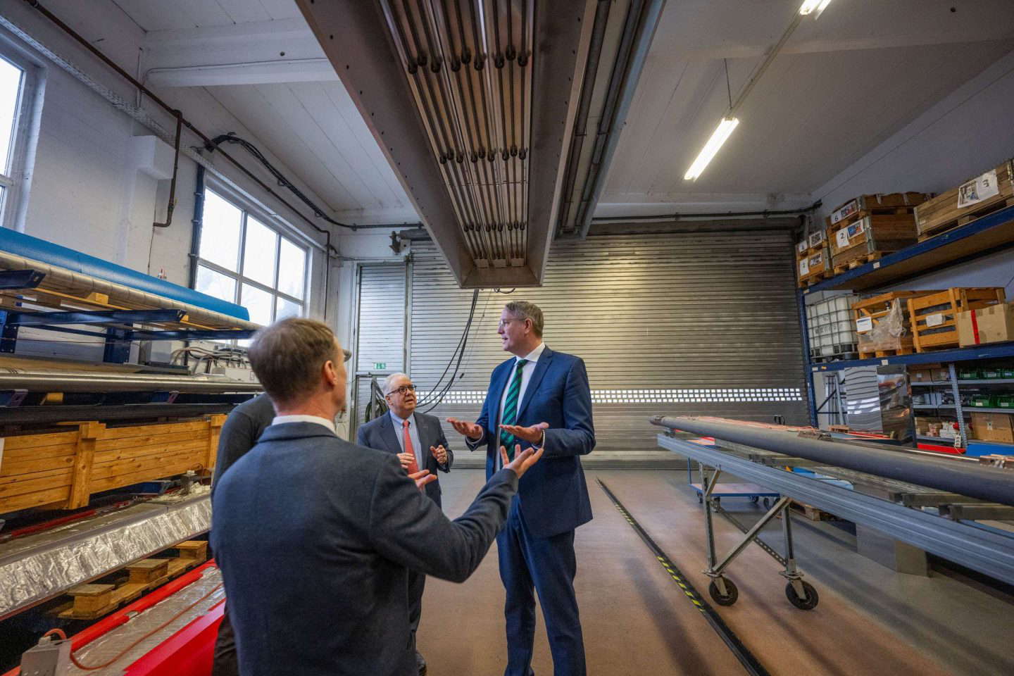 Drei Herren diskutieren in einer Lagerhalle