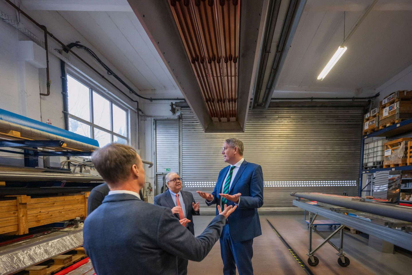 Drei Männer sprechen in einer Fabrikhalle