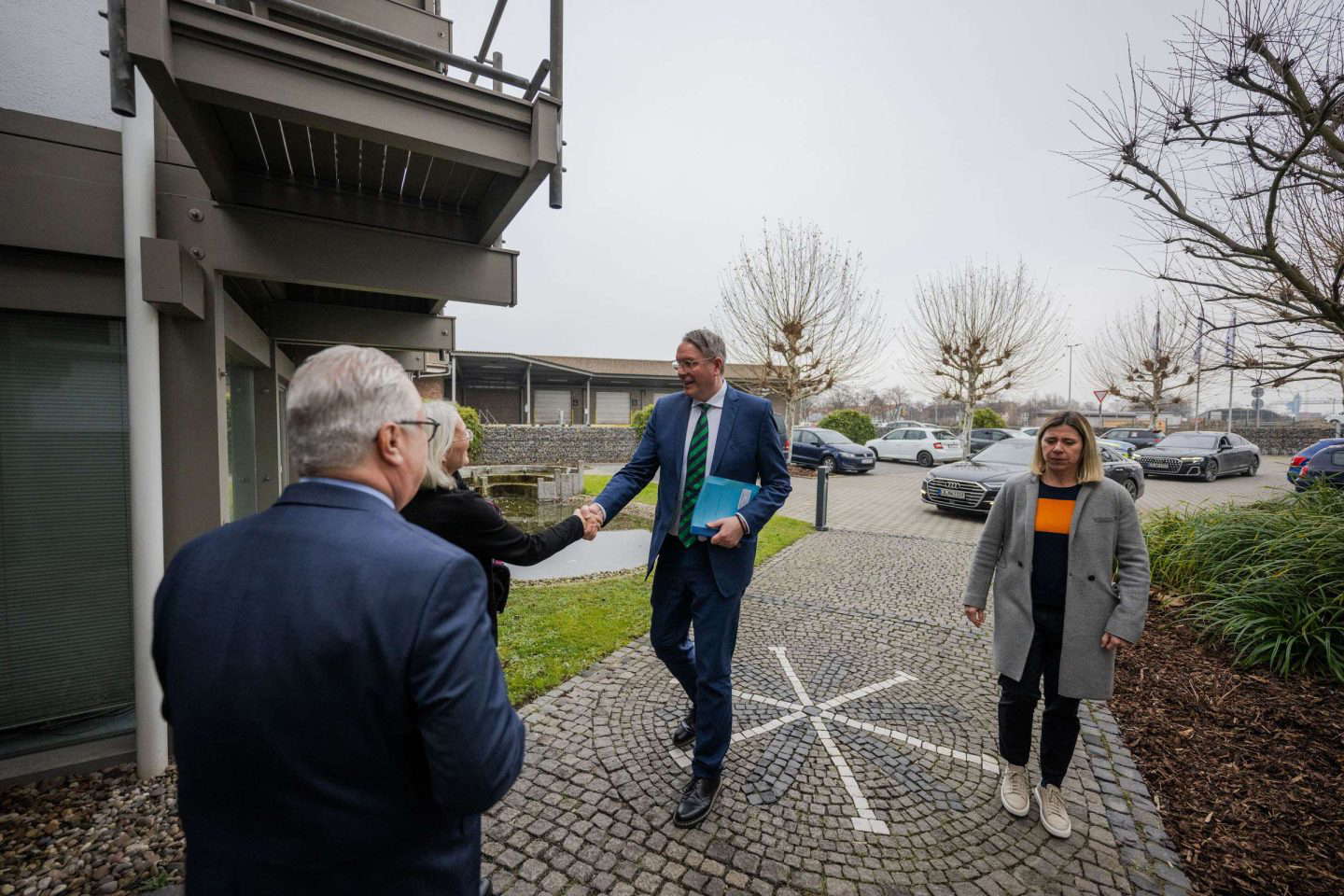 Drei Personen begrüßen sich draußen