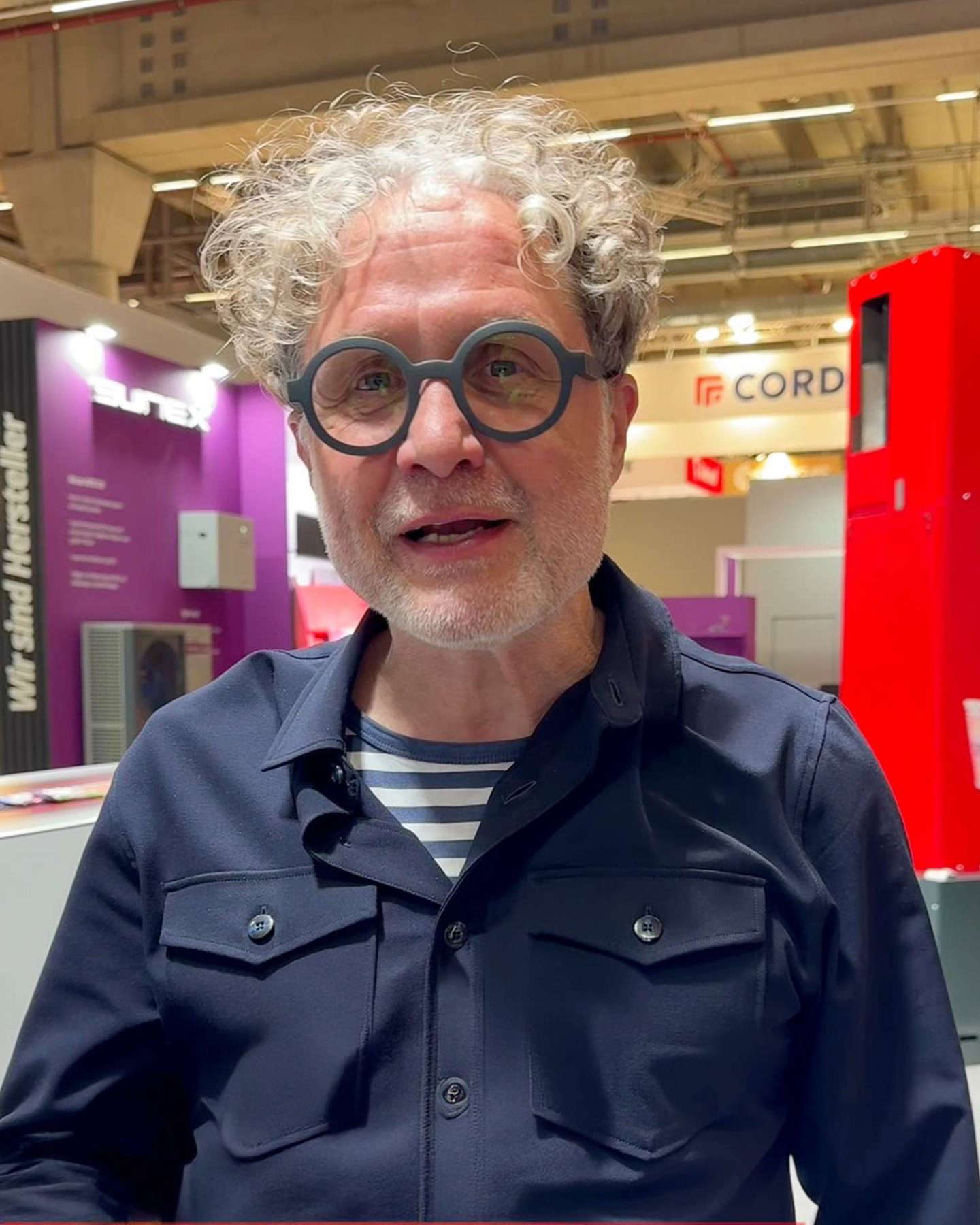 Älterer Mann mit lockigen grauen Haaren und runden Brillen