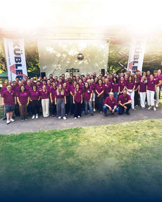 Suuri joukko violetteihin paitoihin pukeutuneita ihmisiä lavan edustalla.