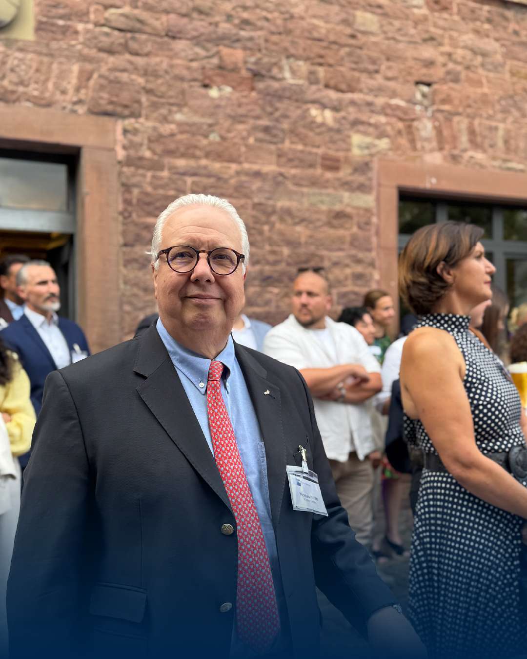 Eldre herre i dress foran historisk bygning