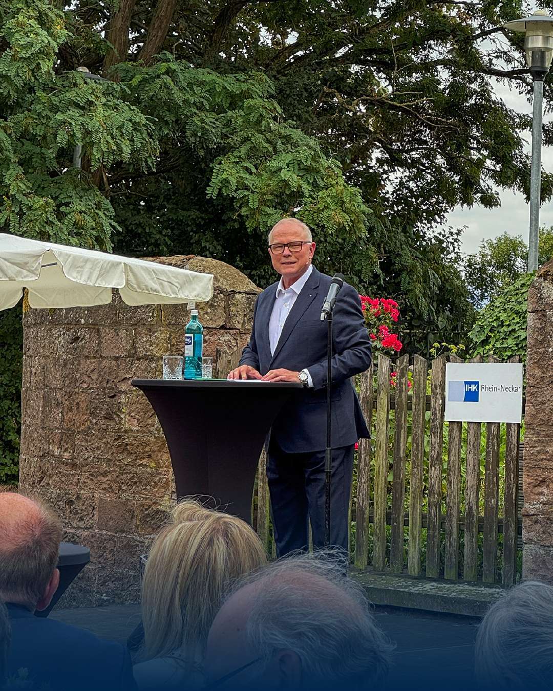 Mann holder tale på utendørsarrangement