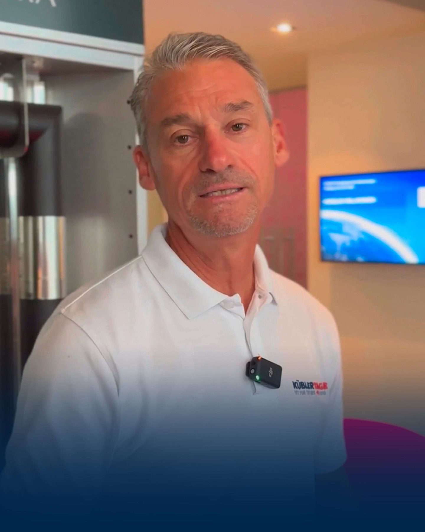 Mann in weißem Poloshirt mit Mikrofon spricht