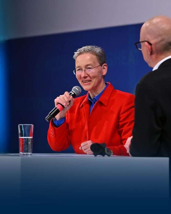 Person spricht mit Mikrofon auf einer Bühne