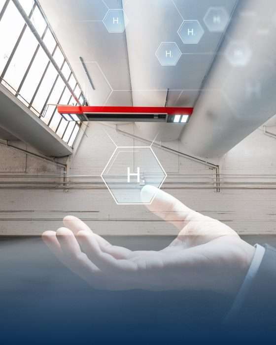 Hand hält Wasserstoffsymbol in moderner Industriehalle