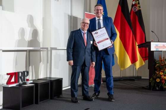 Zwei Männer bei einer Preisverleihung mit Urkunde